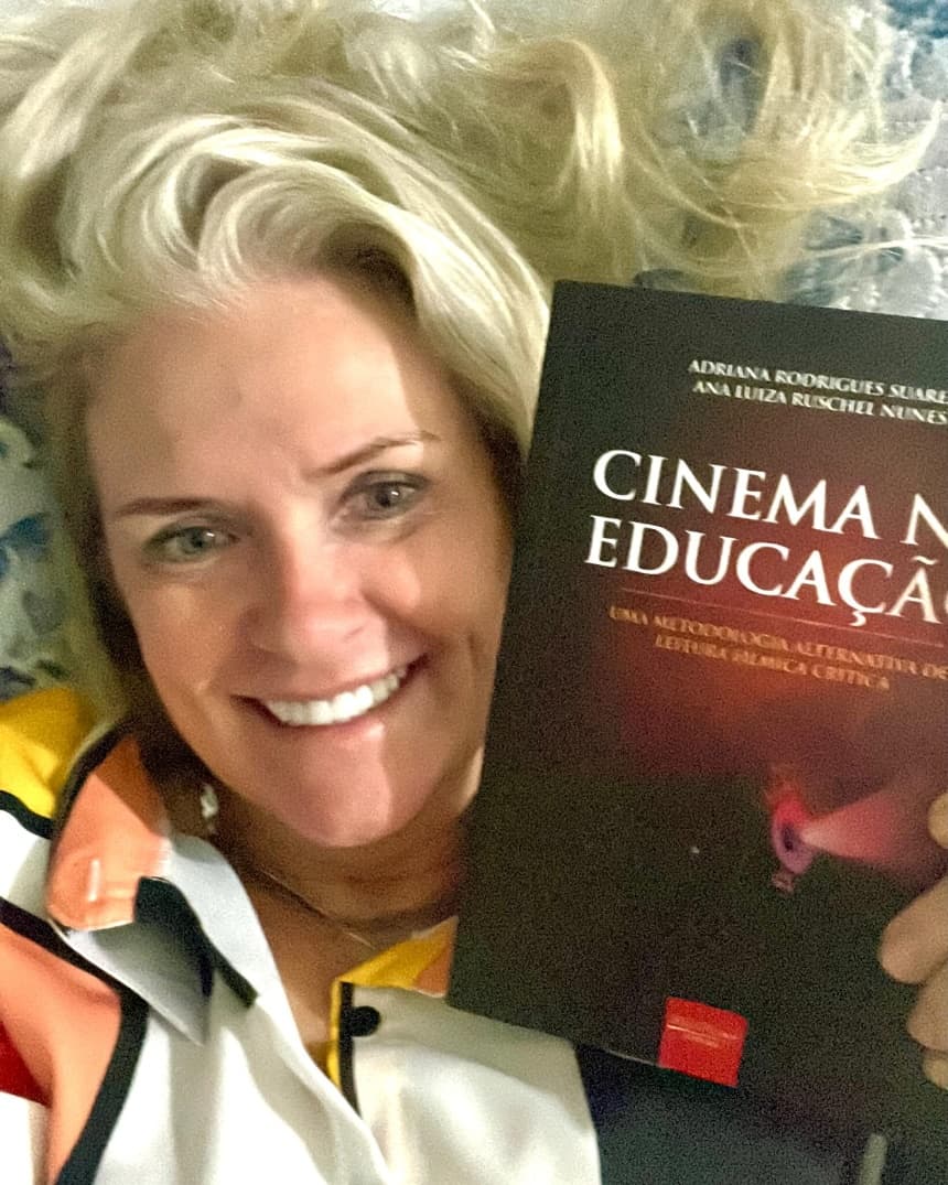 Adriana Rodrigues Suarez segura exemplar do livro "Cinema na Educação"