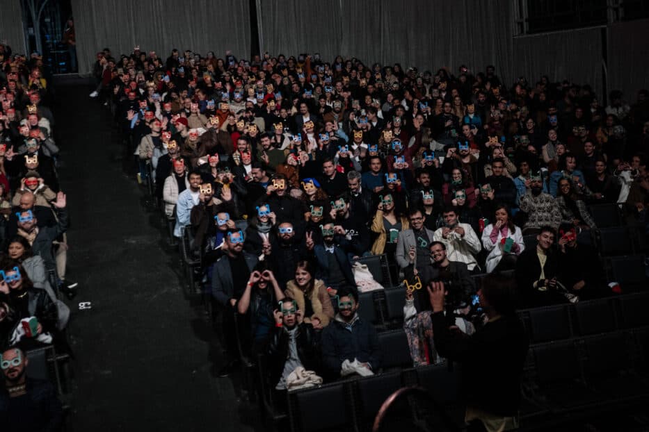 Plateia lotada em sessão do Olhar de Cinema, com óculos personalizados do festival